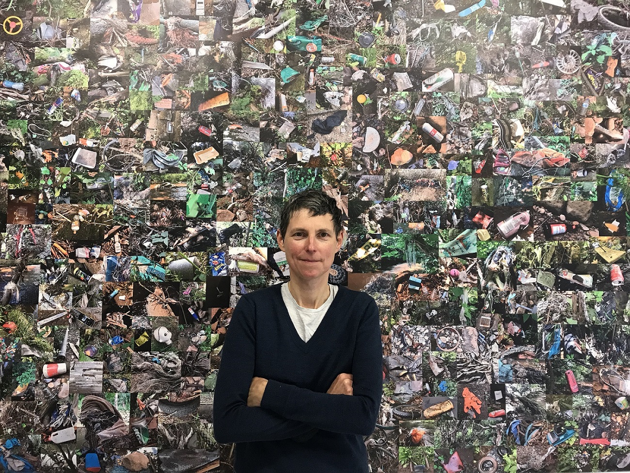 Sound artist Jo Kennedy standing in front of a collage of photos of litter